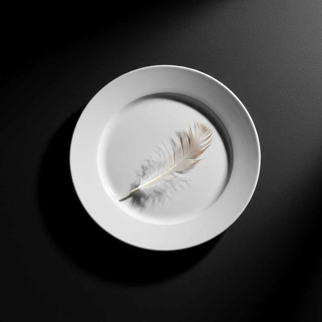 A lone, glossy porcelain dinner plate sits at the center of a seamless matte black table, empty except for a single feather from a chicken, stark white with subtle brown edges and rich texture. The setting is minimalist and devoid of clutter, drawing attention completely to the plate and feather. Hard, directional lighting from stage right casts crisp, deep-edged shadows across the table, emphasizing the plate’s curve and the feather’s delicate barbs. The mood is intensely bold and confrontational, urging reflection on what’s missing. Shot from a high, slightly tilted angle in photographic realism, the image’s sharp focus and uncluttered background evoke a sense of urgency, underscoring the advocacy for animals and a plea to stop eating meat.
